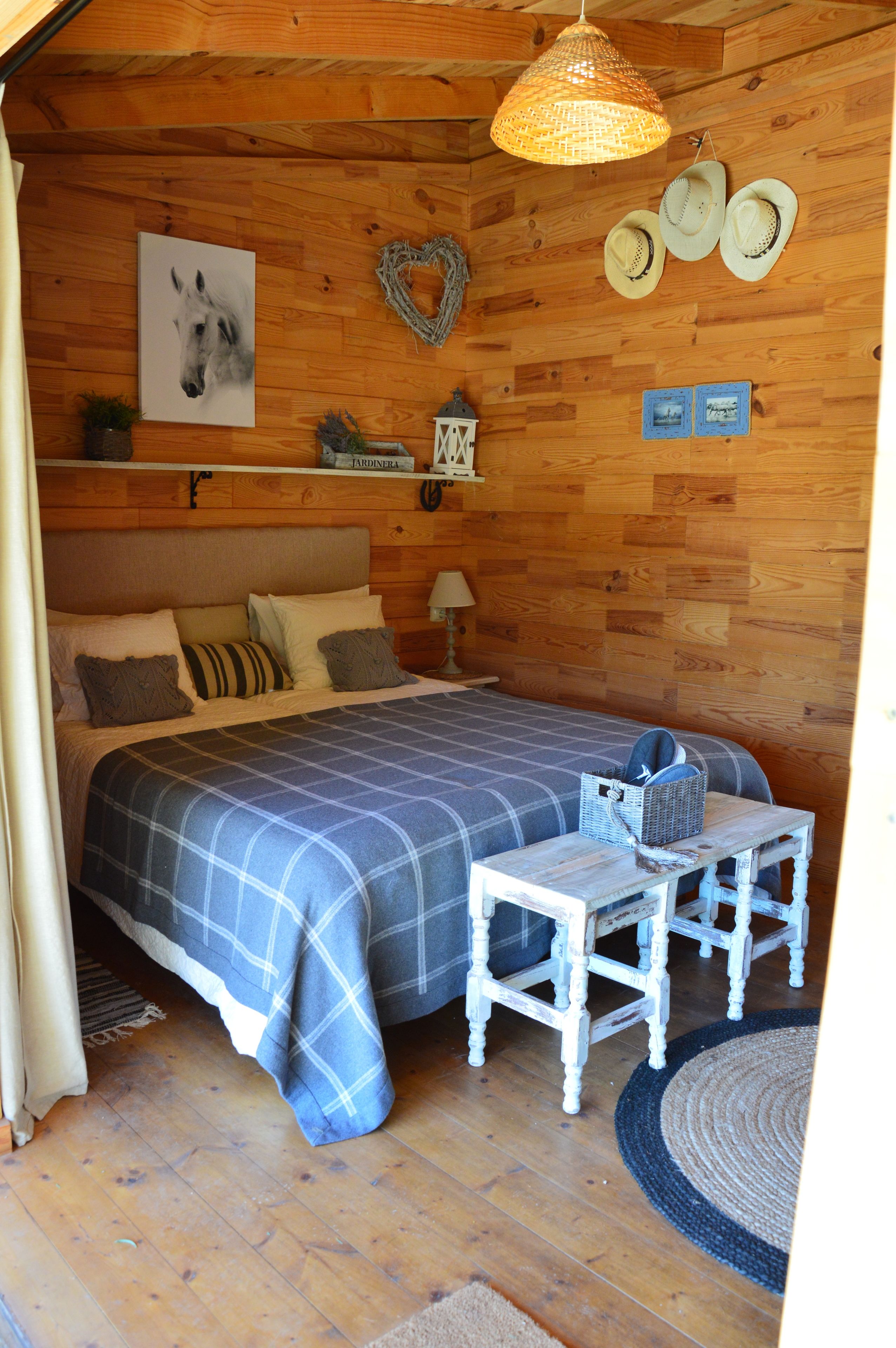 Una habitación acogedora con una cama, una mesita pequeña y una lámpara colgante.