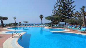 A swimming pool with lounge chairs, surrounded by trees and a clear sky. - Villaggio La Pizzuta (Parghelia)