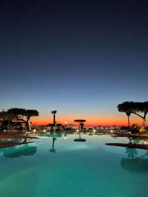 A pool with a sunset view, surrounded by trees and outdoor seating. - Villaggio La Pizzuta (Parghelia)