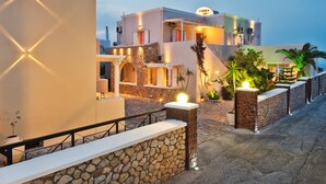 A hotel with a stone facade, outdoor seating, and a well-lit entrance. - Gianna Suites (Santorini)