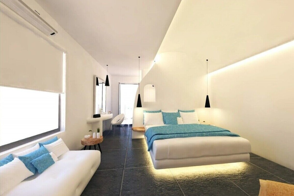 Una habitación de hotel moderna con cama, sofá, una mesita redonda y una silla.
