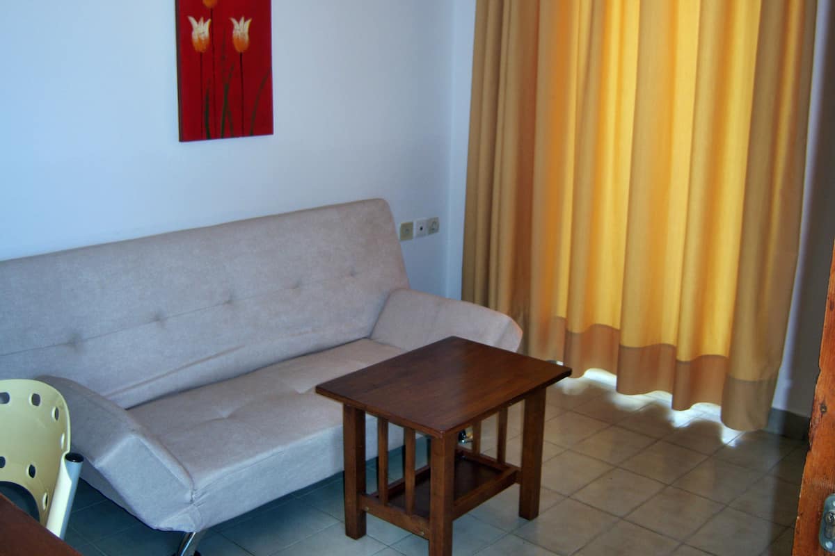 Un salon avec un canapé beige, une table basse en bois et un fauteuil jaune.