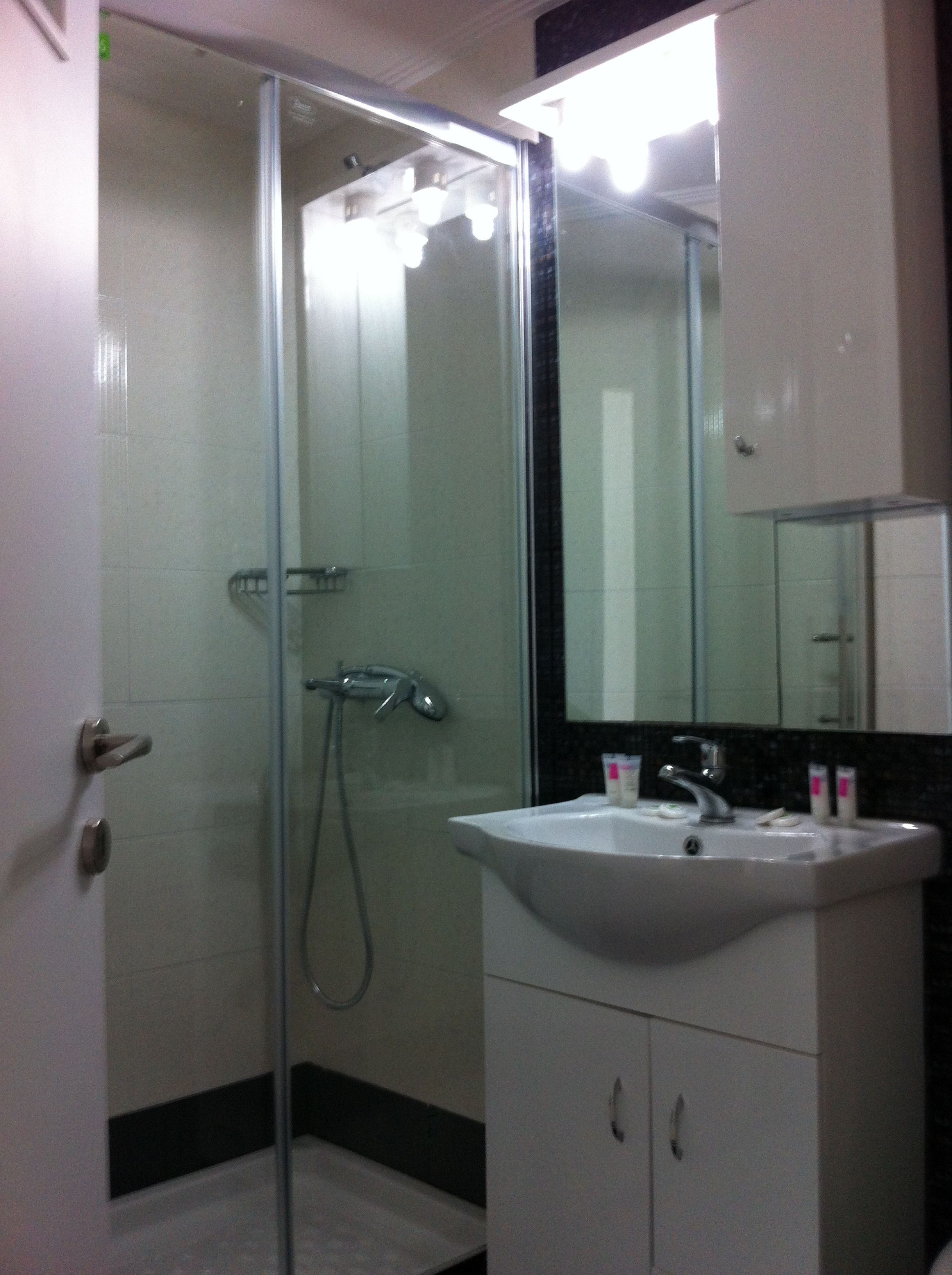 Une salle de bain avec une douche à parois de verre, un lavabo avec un miroir au-dessus et un meuble en dessous.