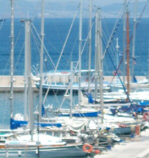 Ein Yachthafen mit mehreren angedockten Booten, einer Mole und Blick auf das Meer.