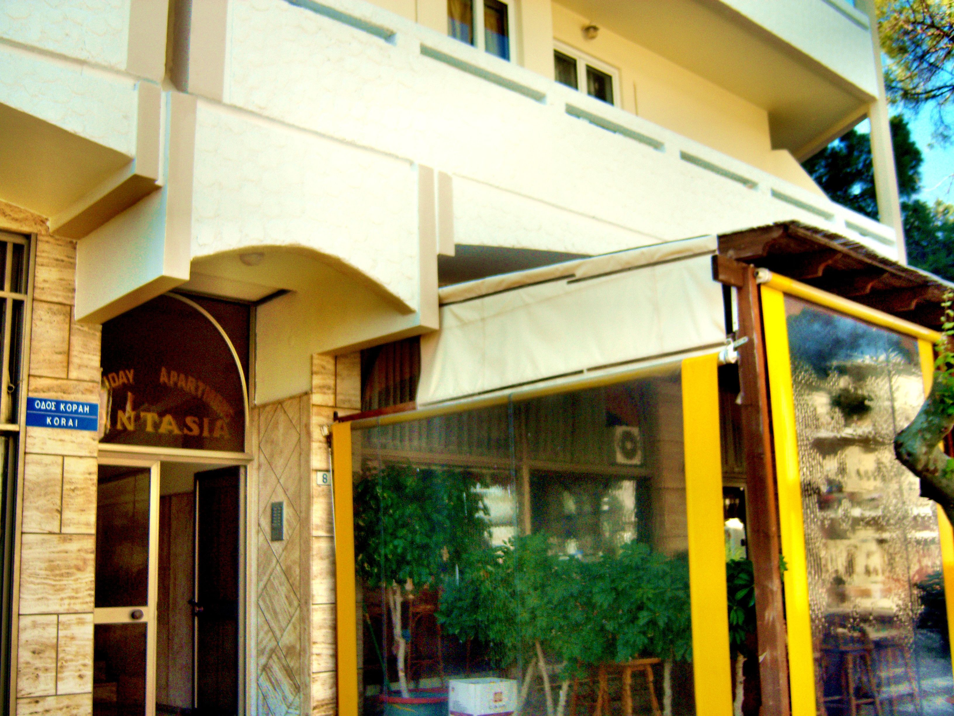 A building with a sign reading "Intasia" and a blue sign with "OAOE KOPAH KORA".