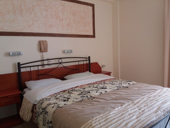 A neatly made bed with a patterned bedspread, a wooden headboard, and a bedside table with a lamp.