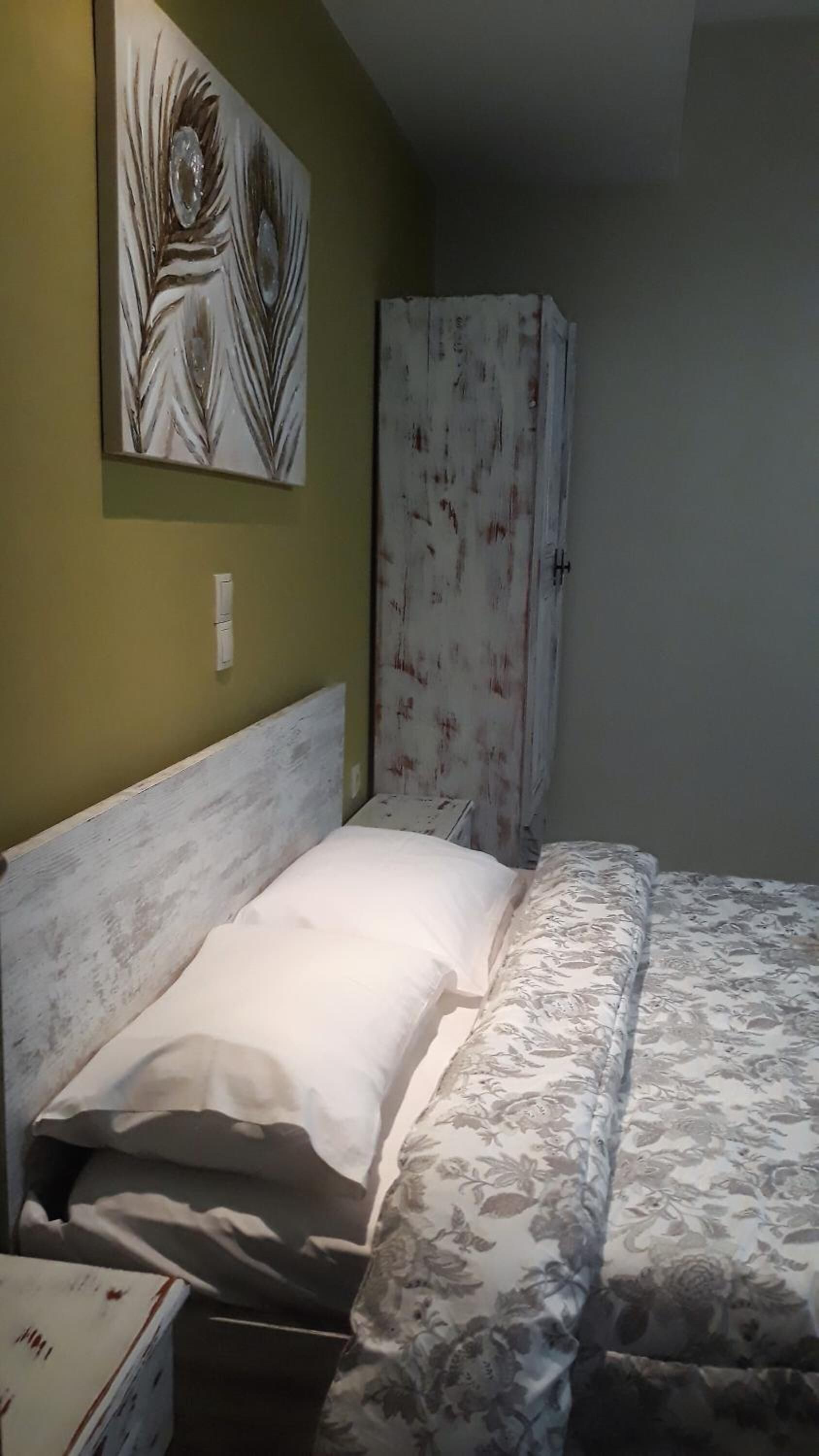 A room with a bed, a wardrobe, and a painting on the wall.