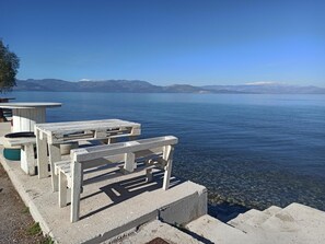 A concrete pier with benches overlooking a calm lake, with mountains in the background.