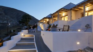 A modern building with a stone staircase leading to a covered outdoor area with seating. - Acropole Sunrise (Santorini)