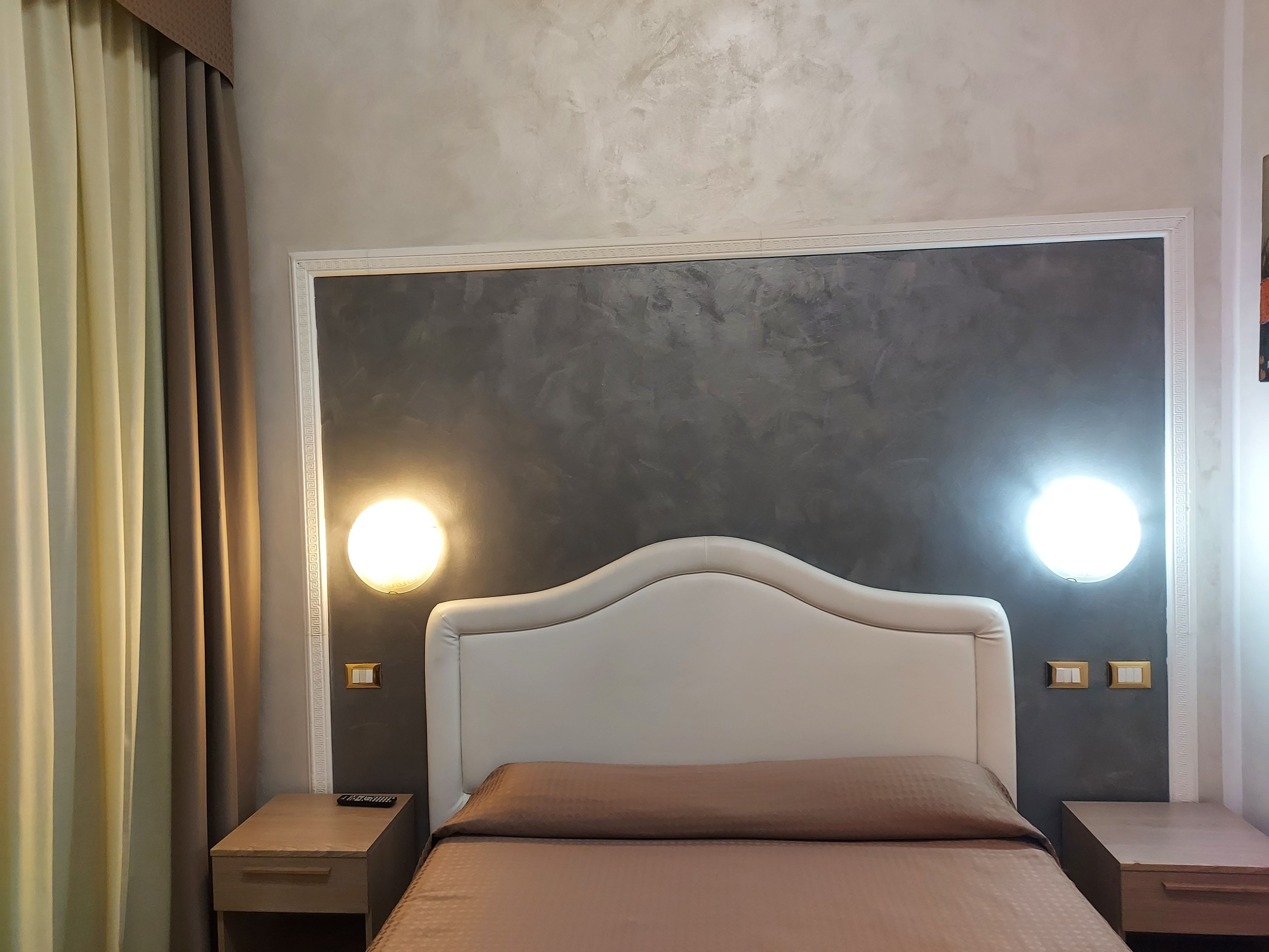 Una camera da letto con un letto grande, due comodini e una lampada a parete.