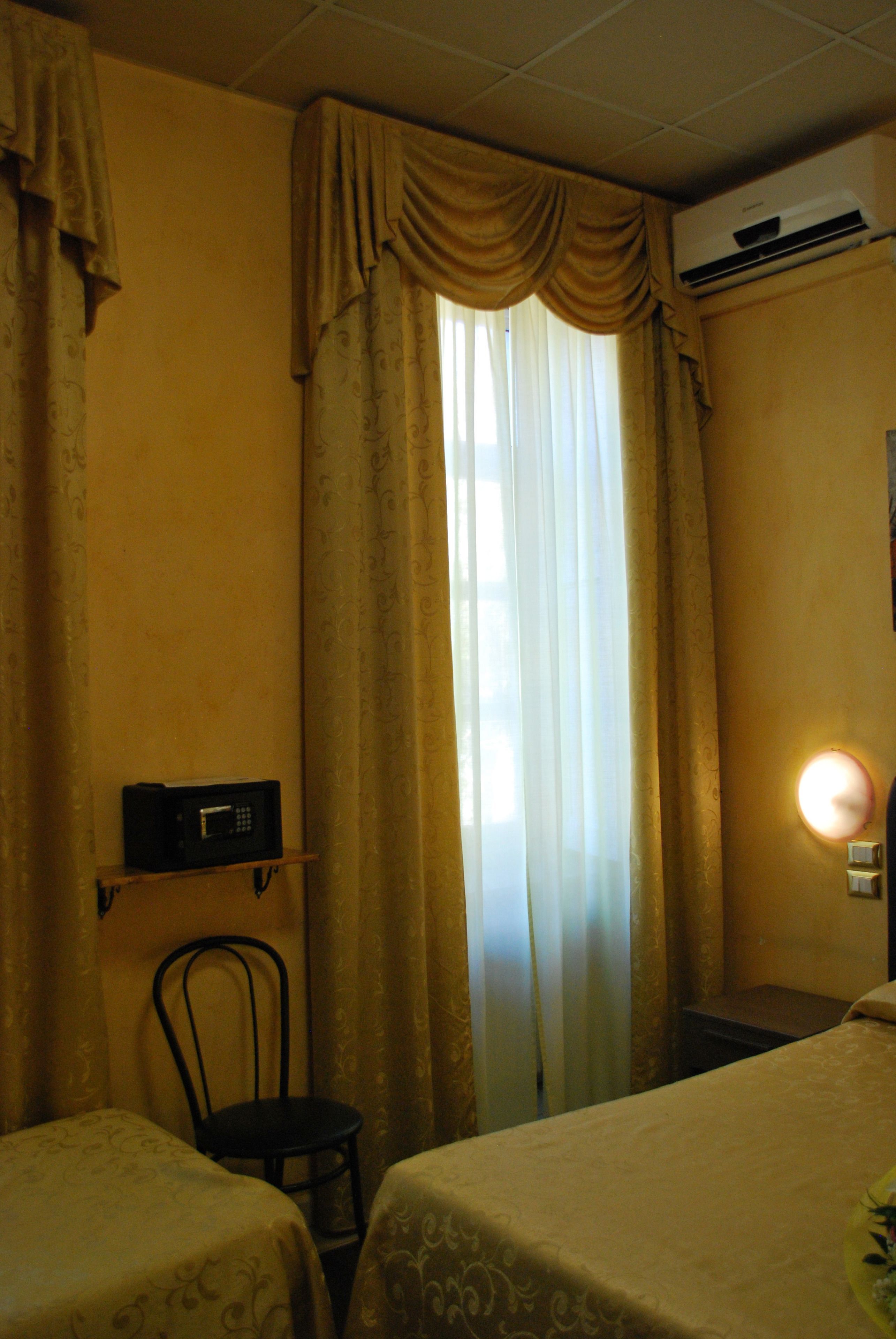 A hotel room with two beds, a chair, a microwave, and an air conditioning unit.
