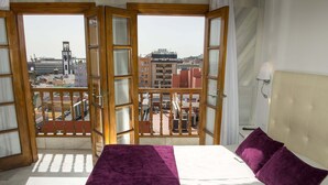 A room with a bed, a view of buildings through open doors, and a balcony railing. - Boutique Océano - Adults Only (Santa Cruz de Tenerife)