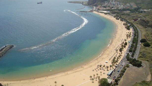 A coastal beach with a road running parallel to the shore, palm trees, and a hilly landscape in the background. - Boutique Océano - Adults Only (Santa Cruz de Tenerife)