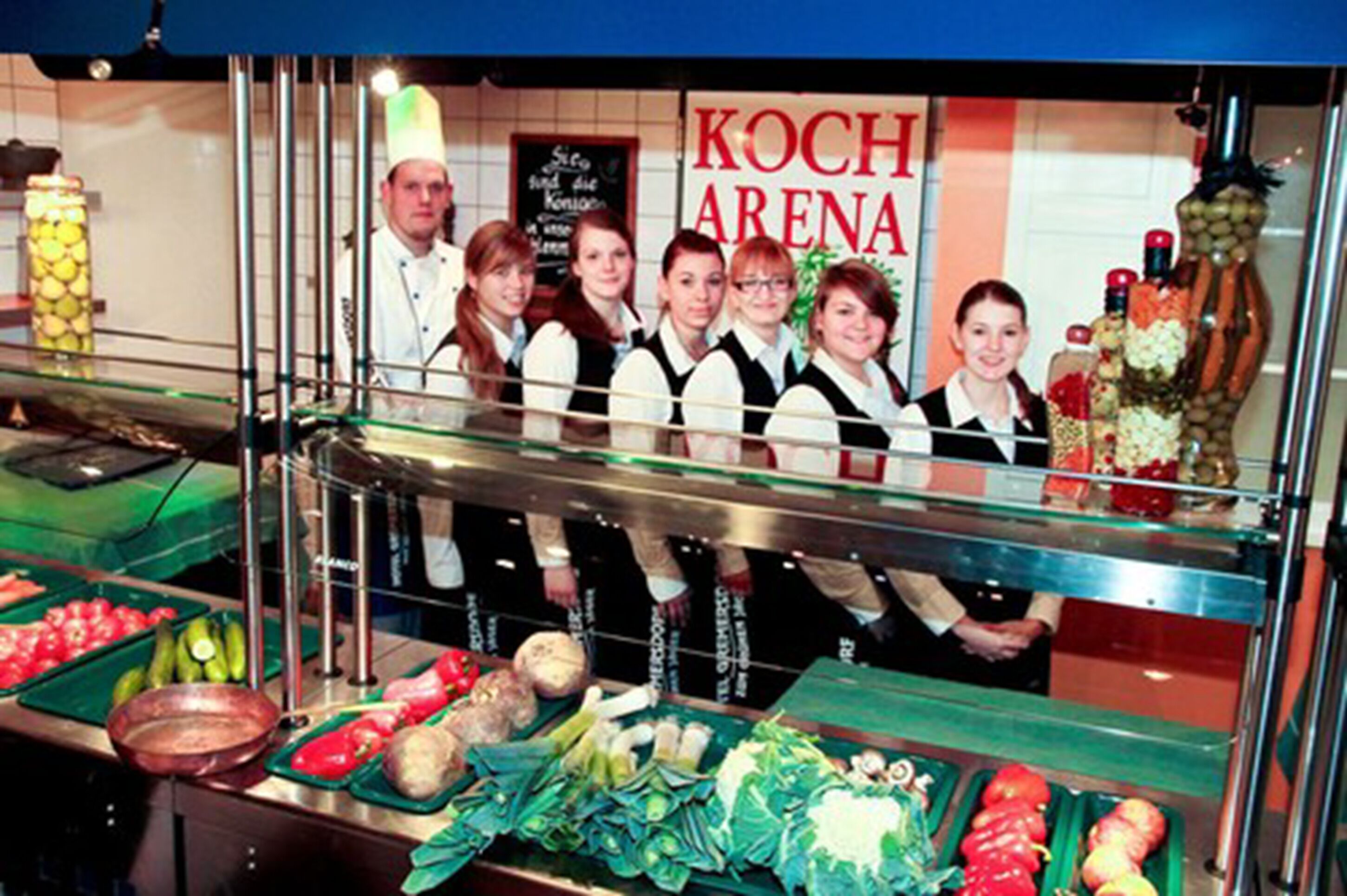 Un espace buffet proposant divers plats et une pancarte indiquant « KOCH ARENA ».
