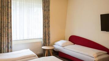 Habitación de hotel con dos camas, una mesita redonda y una ventana con cortinas.