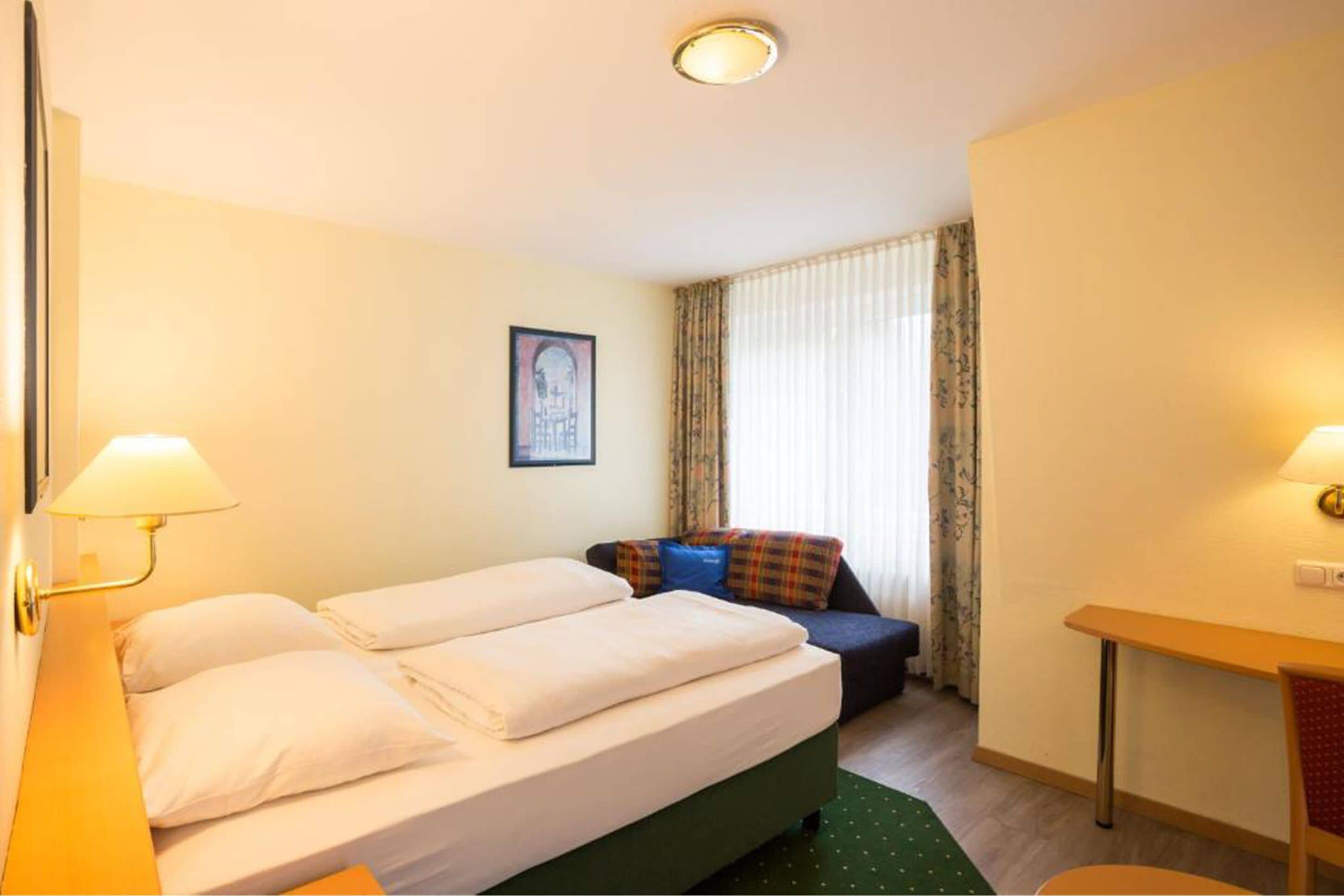 Una habitación de hotel con una cama, un escritorio y una silla.