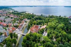An aerial view of a city with a river running through it, surrounded by greenery and buildings. - Hotel St. Bruno (Gizycko)