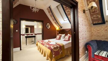 A bedroom with a large bed, a vanity, and a red sofa.
