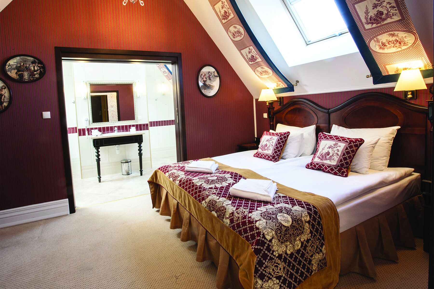 A bedroom with a large bed, a wooden headboard, and a skylight.