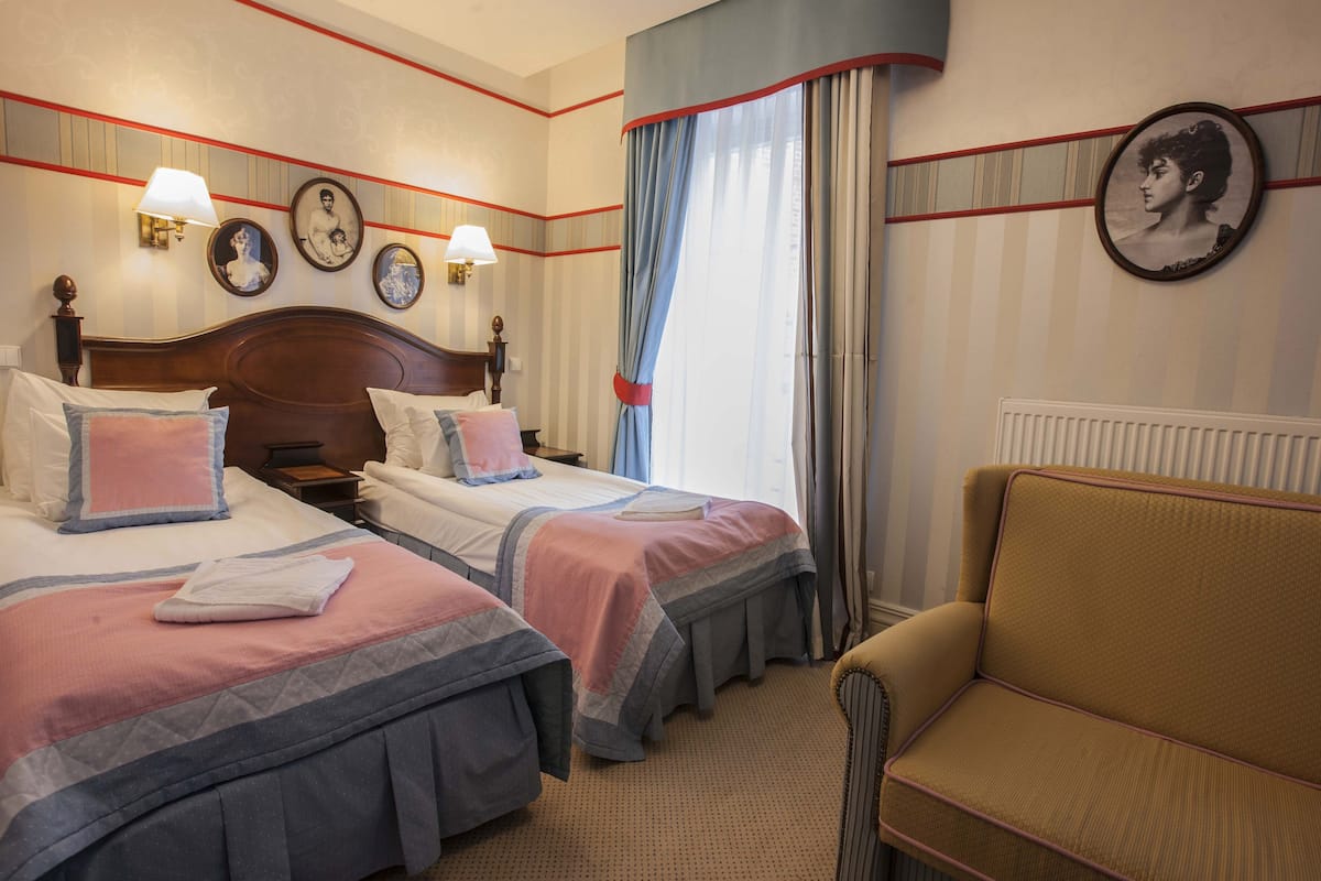 Habitación de hotel con dos camas, un sofá y un radiador.