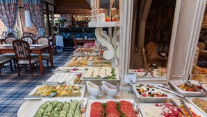En buffet med forskellige retter, herunder skiver agurker, tomater og salater.