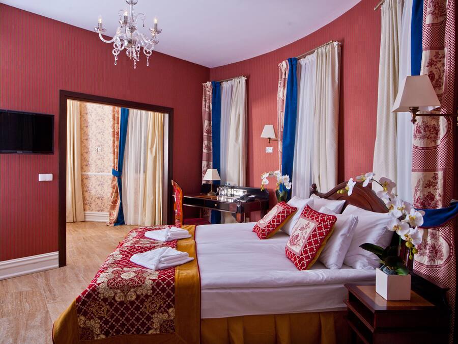 Een hotelkamer met een bed, nachtkastje, lamp en een bureau met stoel.