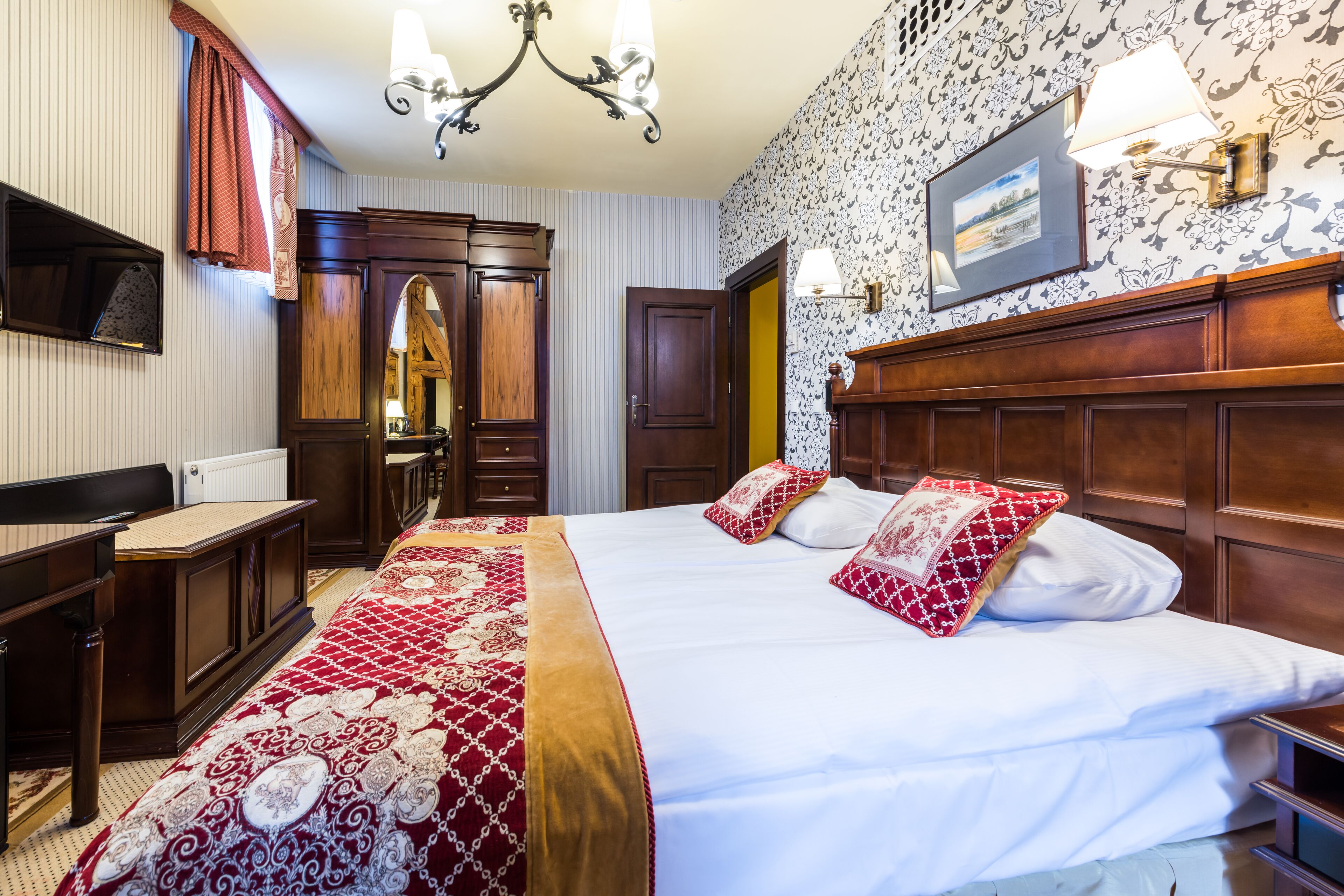 Una habitación de hotel con una cama grande, cabecera de madera, un escritorio y un armario.