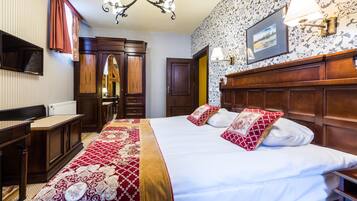 Una habitación de hotel con una cama grande, cabecera de madera, un escritorio y un armario.