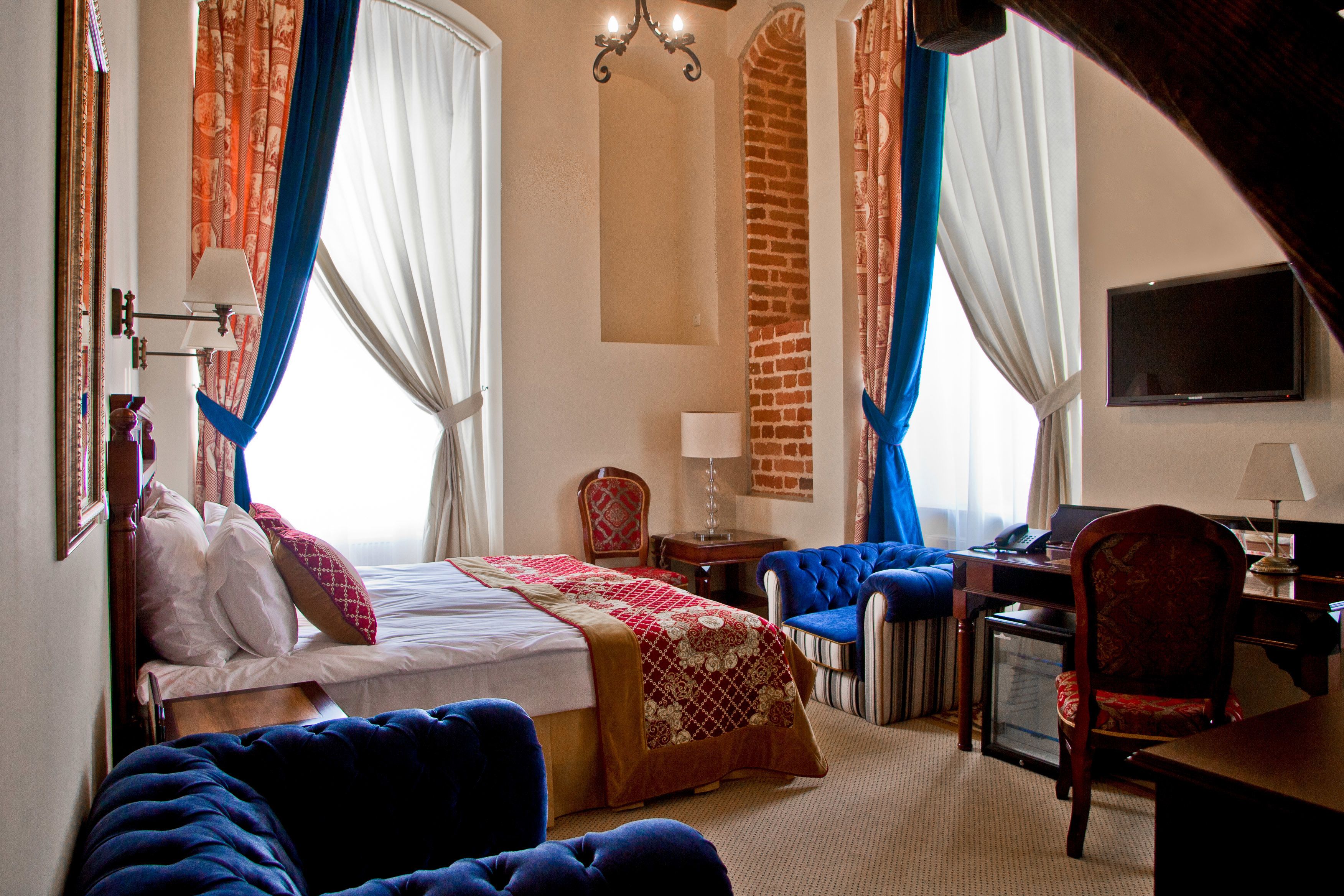 Une chambre d’hôtel avec un lit, un bureau équipé d’un ordinateur, une chaise et un téléviseur.