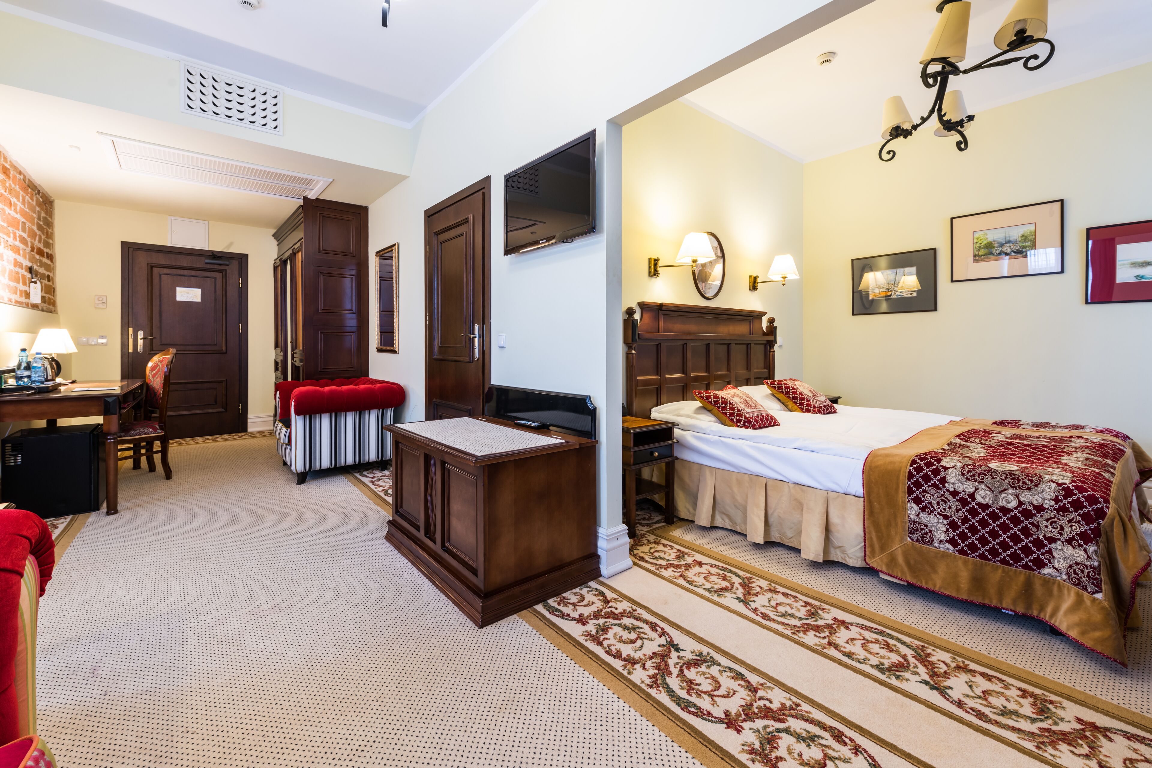 Una habitación de hotel con cama, escritorio, silla, armario y piso alfombrado.