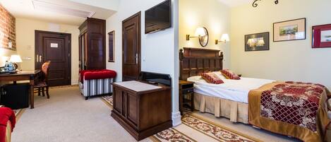 A hotel room with a bed, a desk, a chair, a wardrobe, and a carpeted floor.