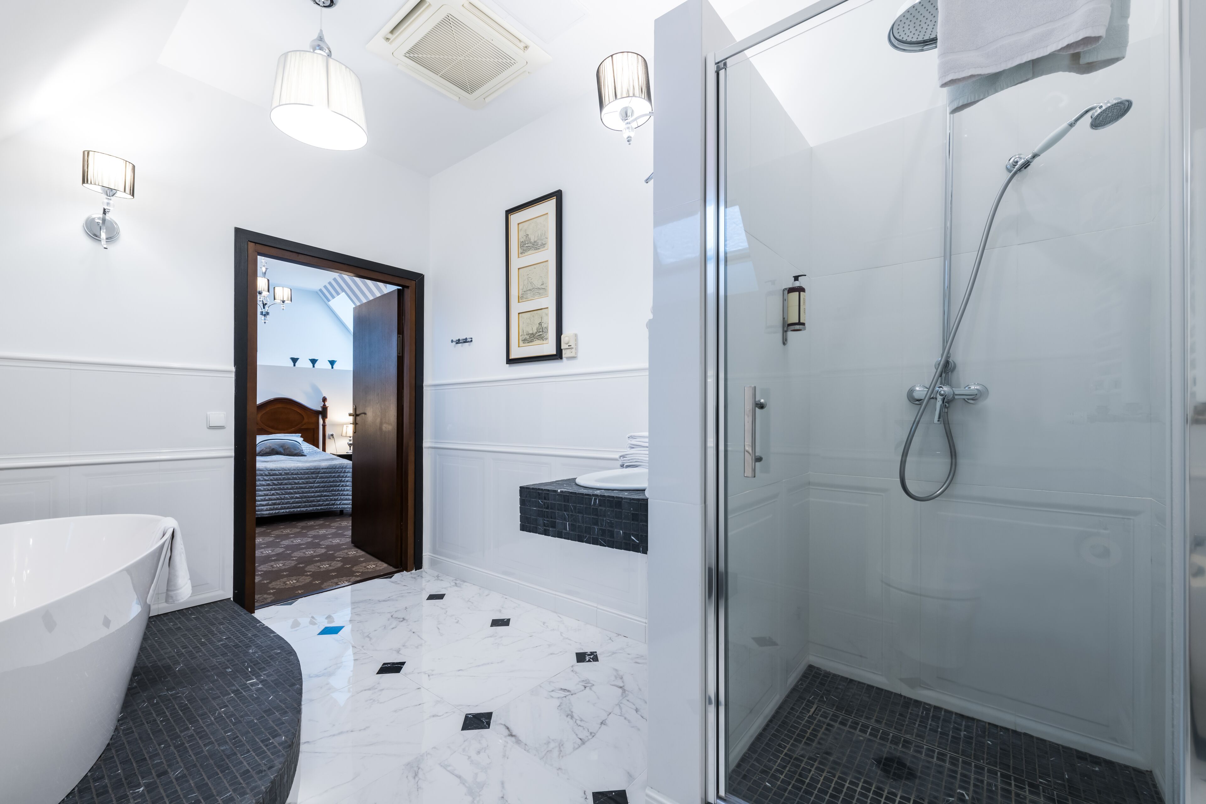 Un baño moderno con una bañera independiente, ducha con mampara de vidrio y tocador con espejo.