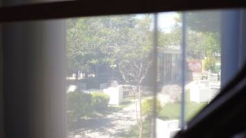 A view through a window with a wooden frame, a small table, and a chair visible in the foreground.