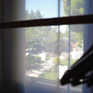 A view through a window with a wooden frame, a small table, and a chair visible in the foreground. - Ege Han Otel (Bozcaada)
