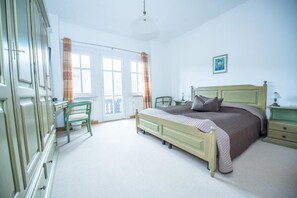 A bedroom with a bed, a dresser, a chair, and a window with curtains. - Bilz Pension (Moritzburg)