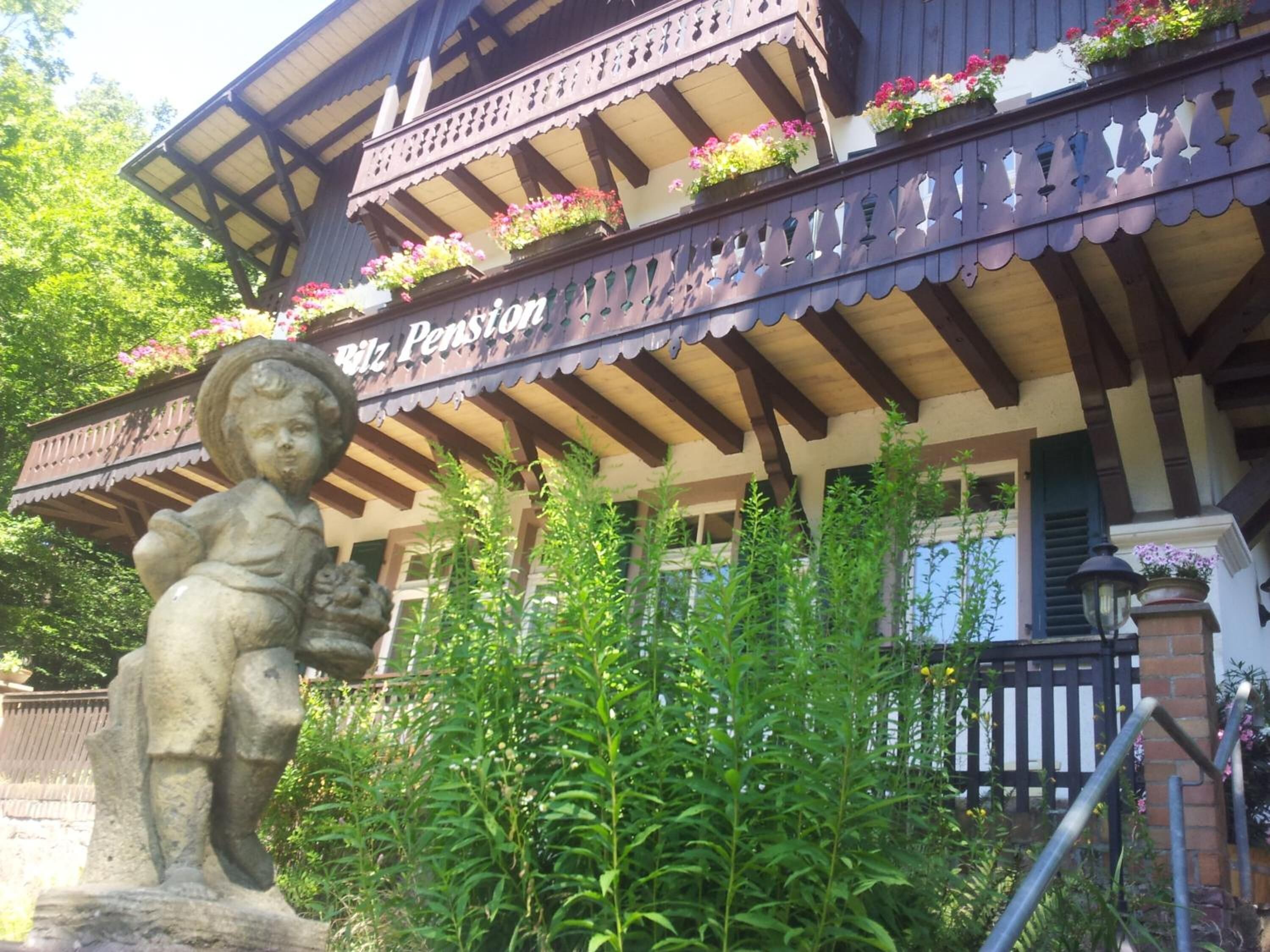 A building with a balcony adorned with flower boxes and a statue of a child.