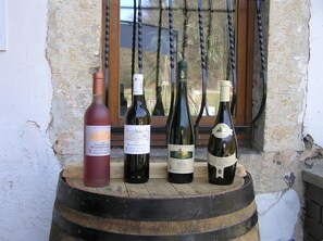 Four wine bottles on a wooden barrel outside a building with a window. - Bilz Pension (Moritzburg)