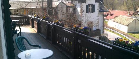 Un balcón con mesa y sillas, con vistas a un pueblo con edificios tradicionales.
