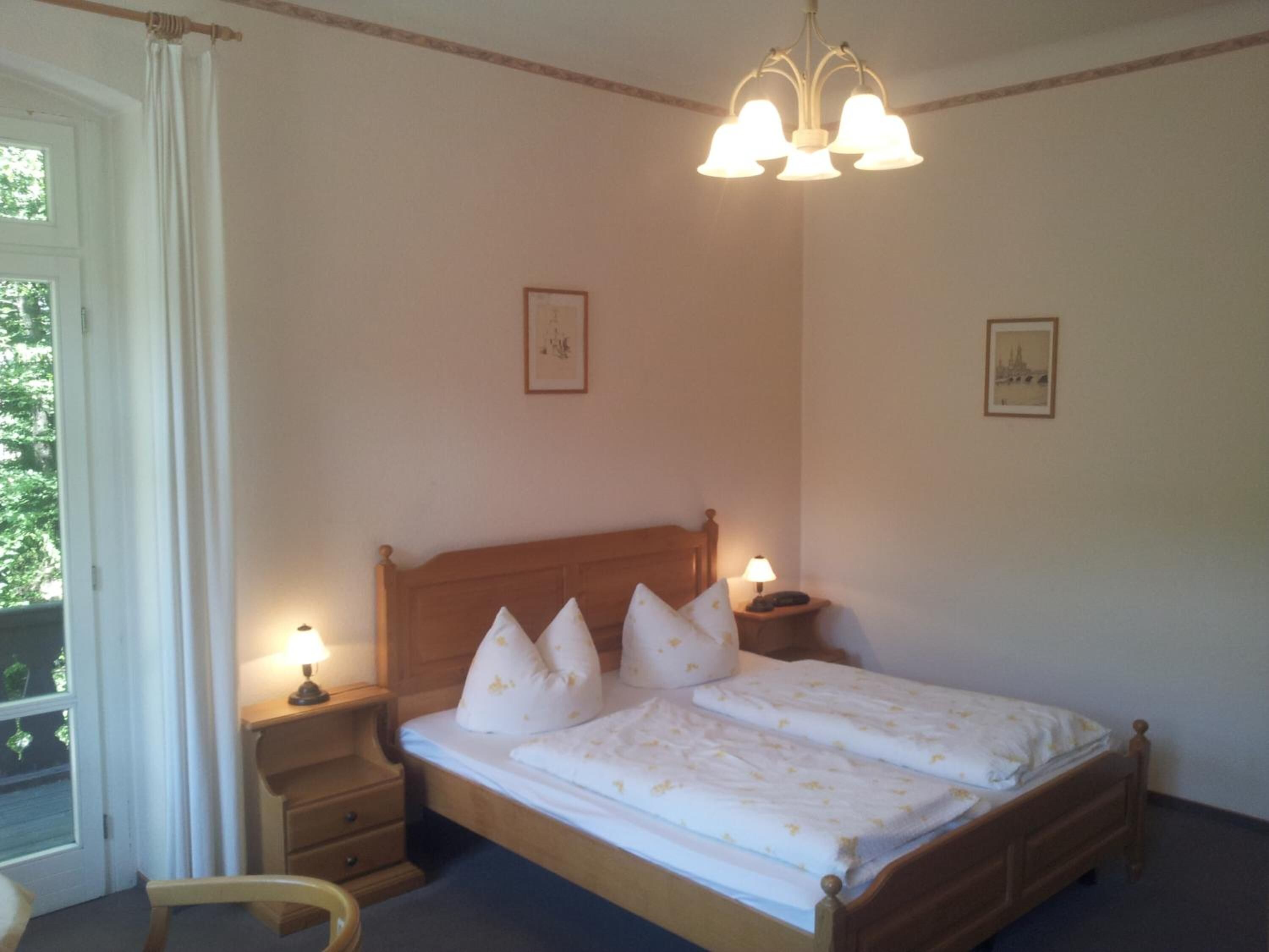 Un dormitorio con cama de madera, lámparas de noche y cuadros en las paredes.