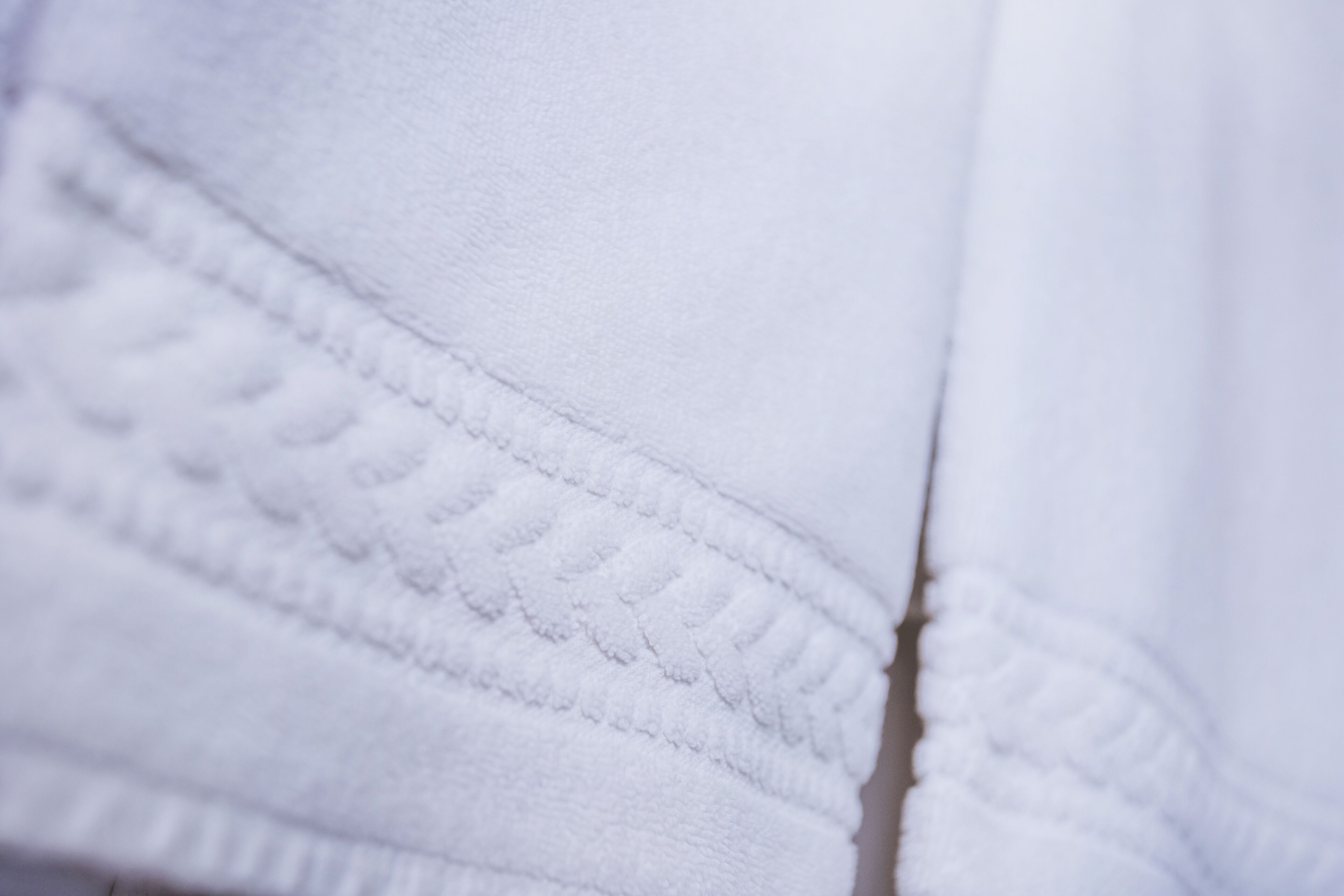 Primer plano de un tejido blanco con un patrón texturizado, probablemente parte de una prenda o tapicería.