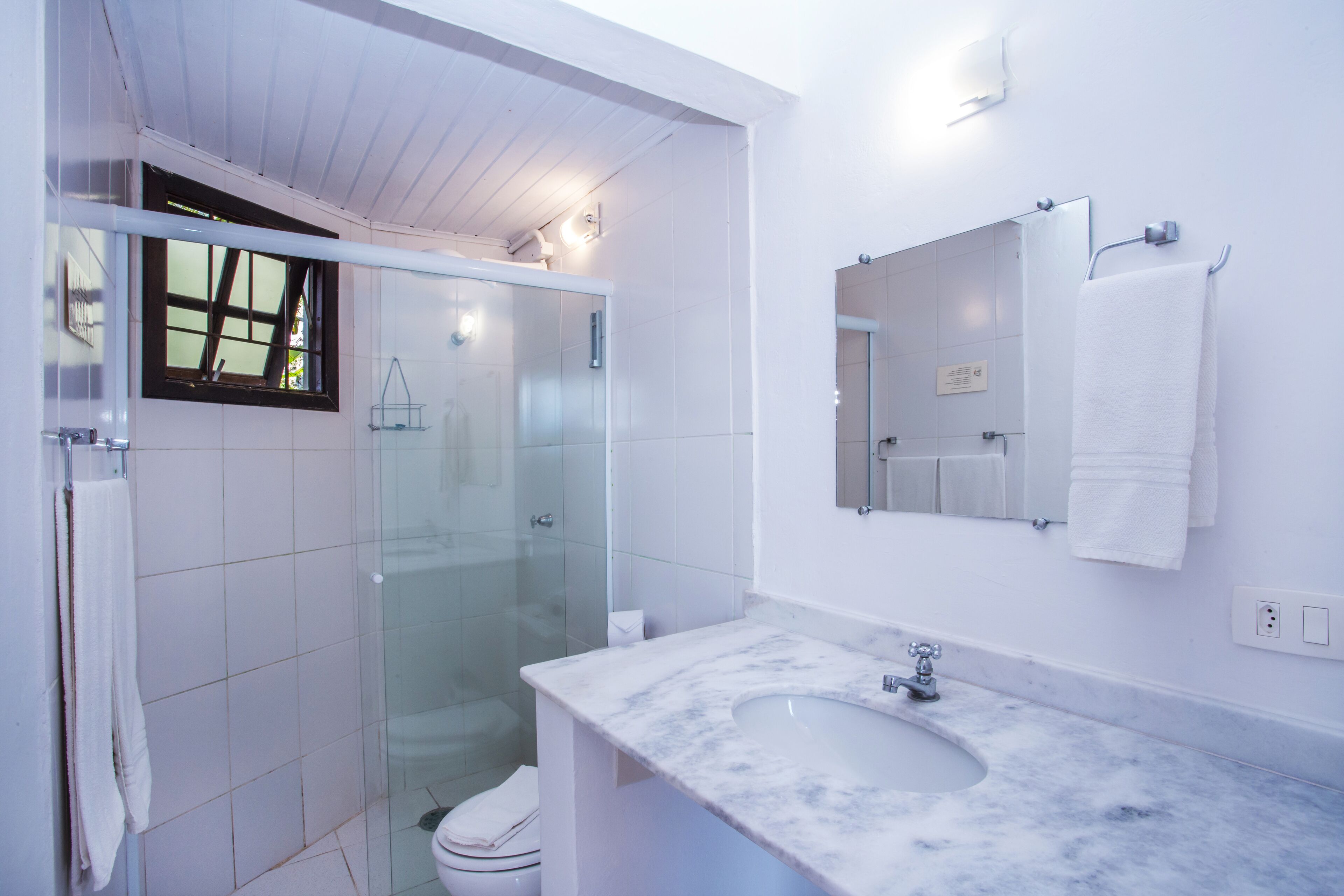 A modern bathroom with a glass shower enclosure, a marble sink, and a large mirror.