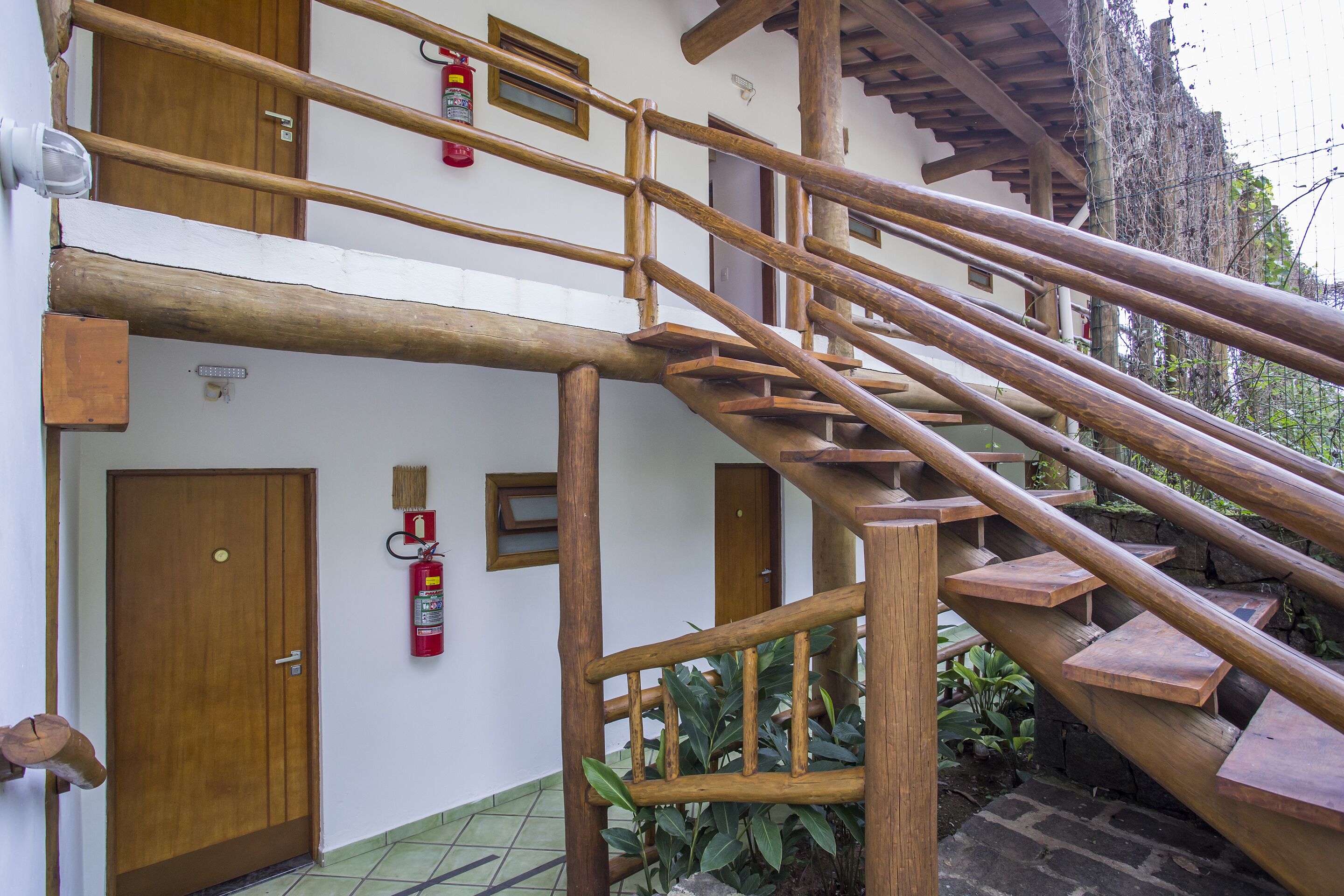 Una escalera de madera con un extintor fijado en la pared.