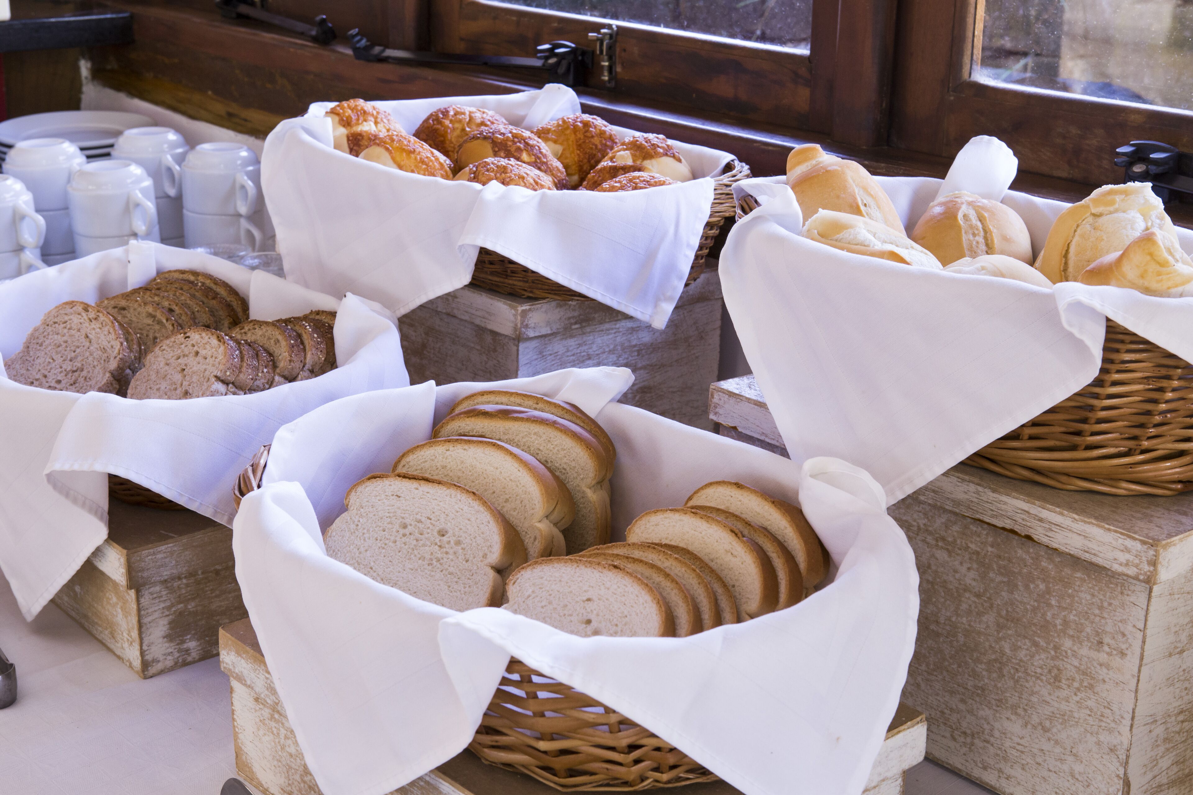A breakfast buffet with various breads and pastries displayed in baskets.