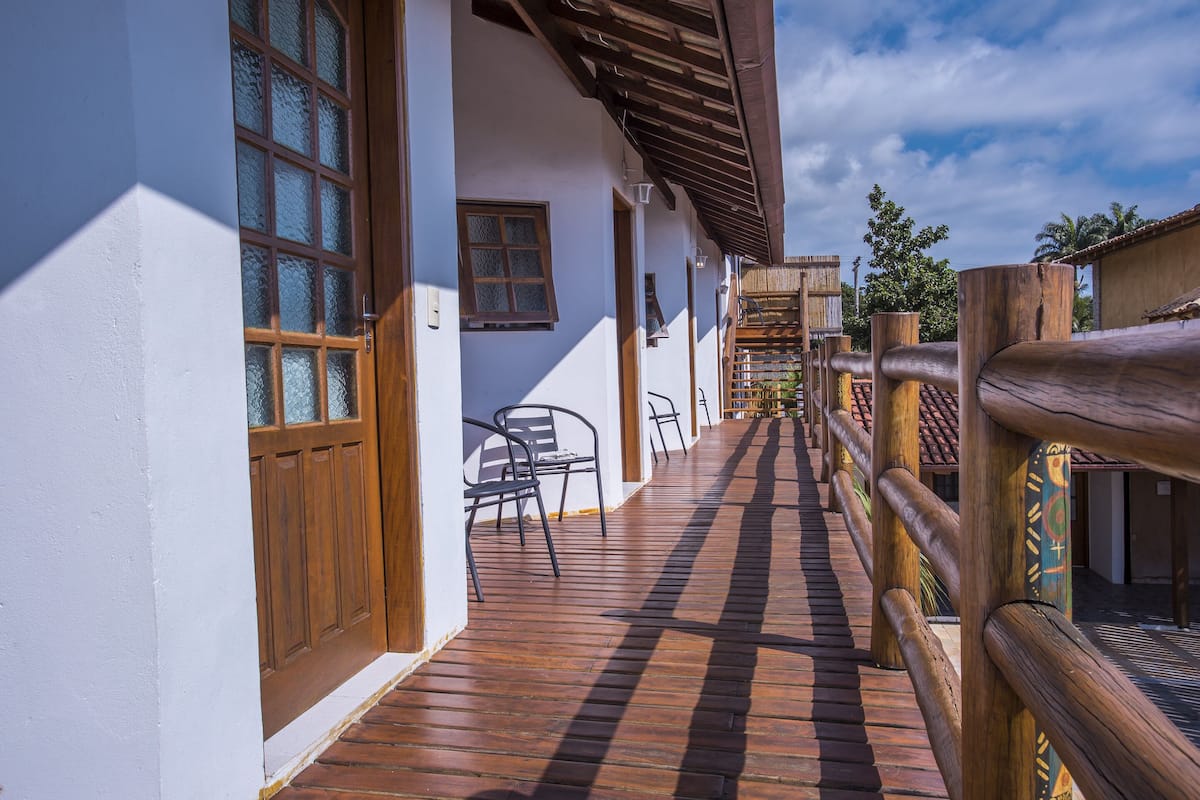 A wooden deck leading to a white building with a wooden door and windows.