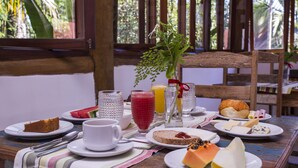 Une table de petit-déjeuner avec des assiettes remplies de nourriture, des verres de jus de fruits et un vase avec des fleurs.
