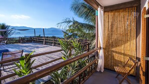 Une terrasse en bois avec une piscine, un mur en bambou et une vue sur les montagnes.