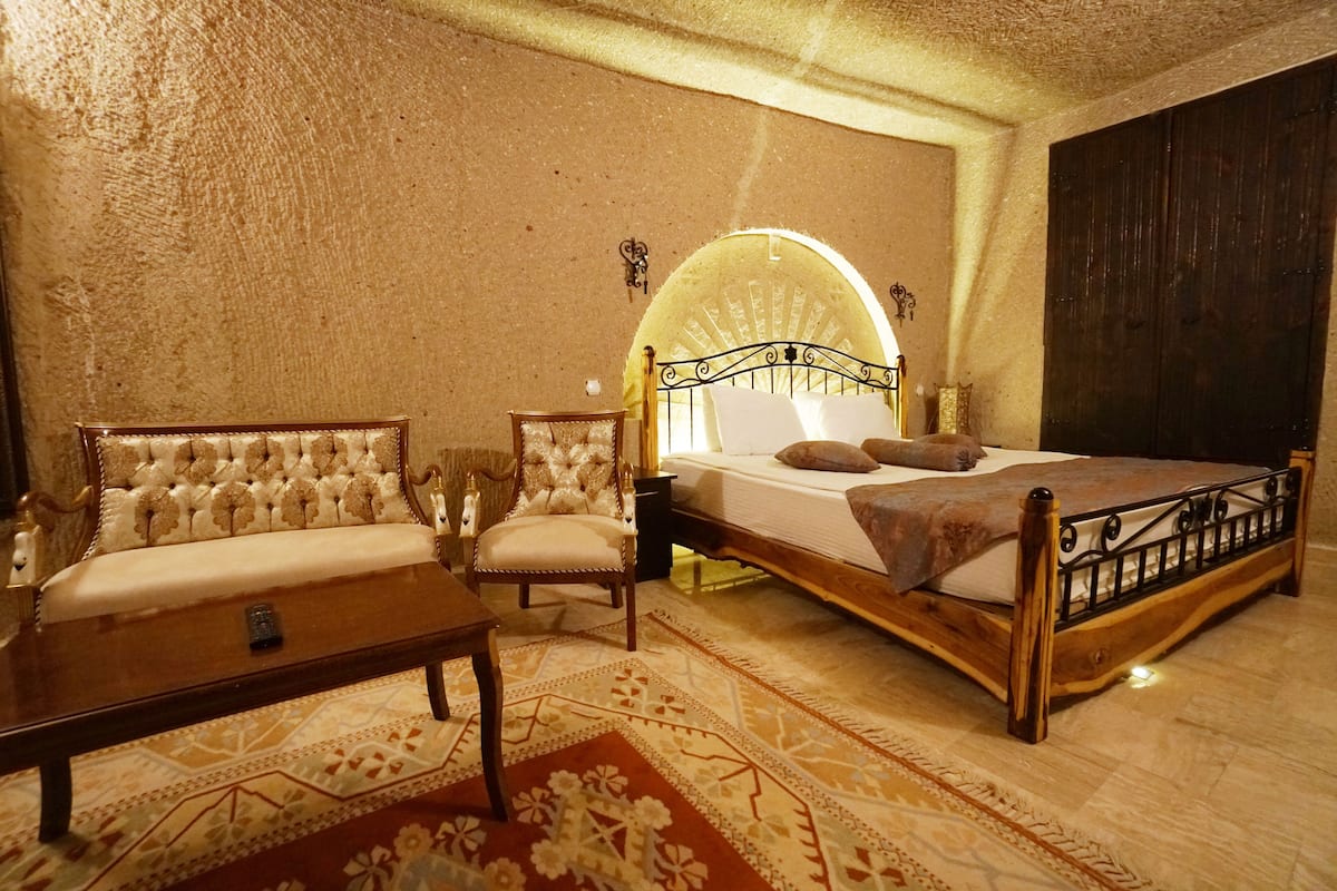 Un dormitorio con una cama de madera, un sofá, una silla y una mesita.