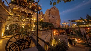 A historic building with multiple balconies, arches, and a large rock formation. - Roma Cave Suite Hotel (Nevsehir)