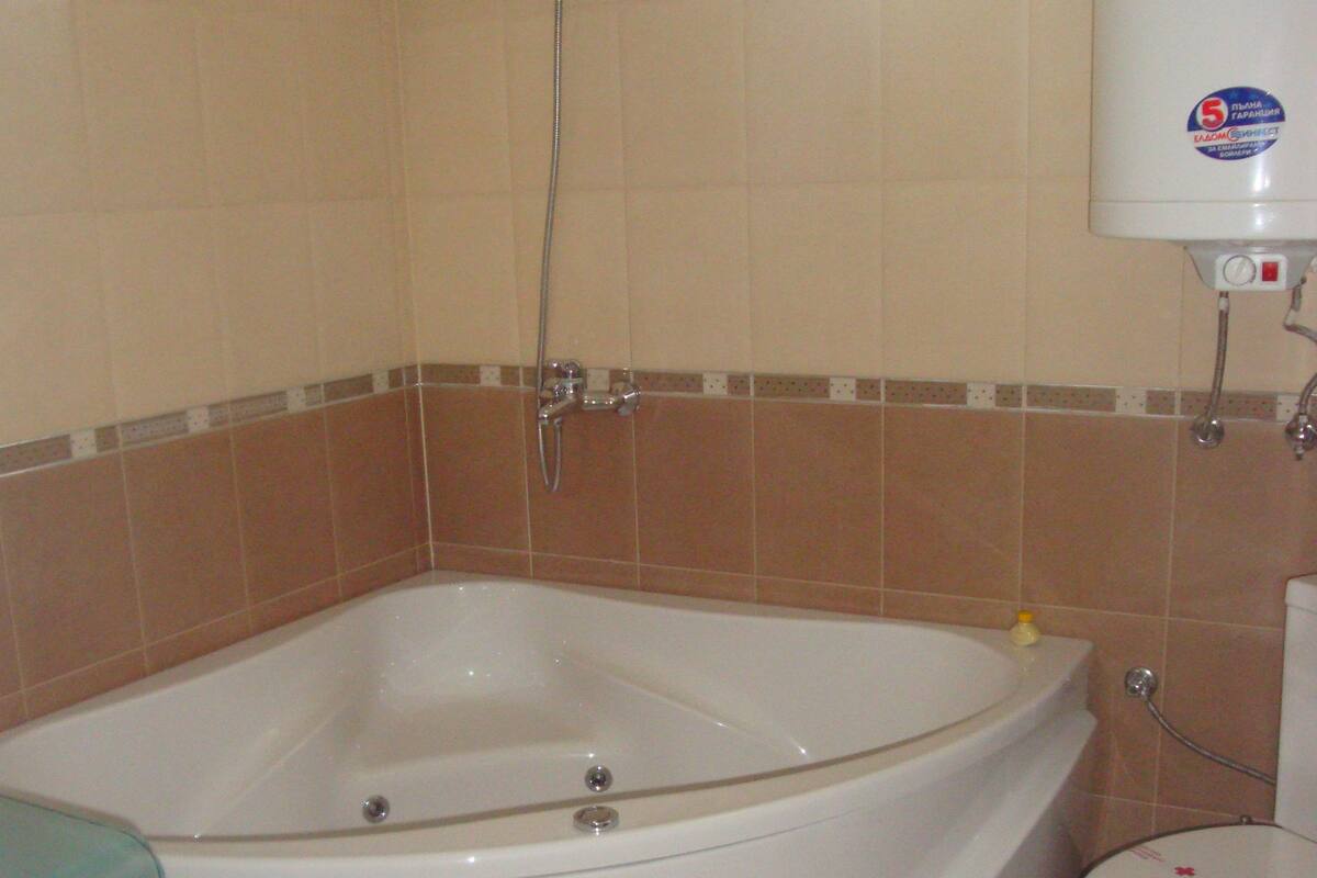 A bathroom with a bathtub, toilet, and a window providing natural light.