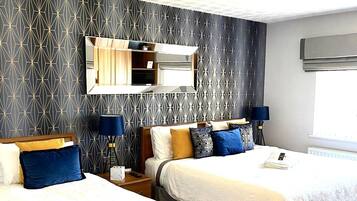 Habitación de hotel con dos camas, un espejo grande y un aplique de techo.